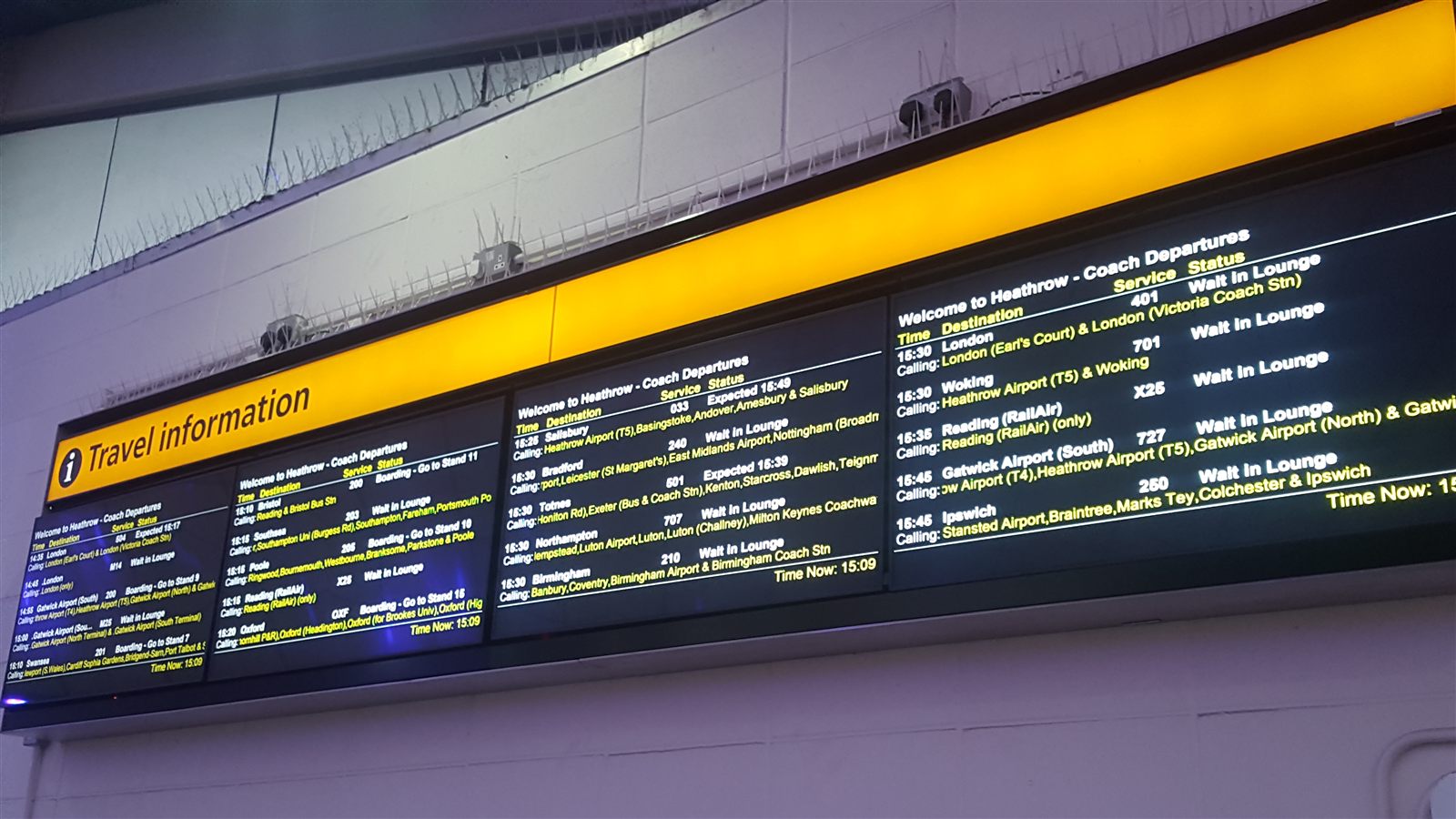Wall of coach departure boards under a Travel information sign at a coach station